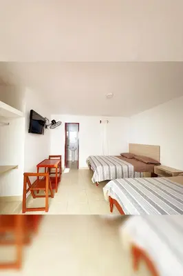 a hotel room with two beds and a table at LAS PALMERAS HOSTAL in Barranca