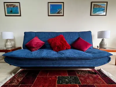 a blue couch with red pillows in a living room at Bonito depa san isidro cama queen home office wifi y cochera in Lima