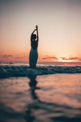 a woman standing on a beach with her leg in the air at VIVEMAR PUNTA HERMOSA - Beach House Lima - Perú in Punta Hermosa