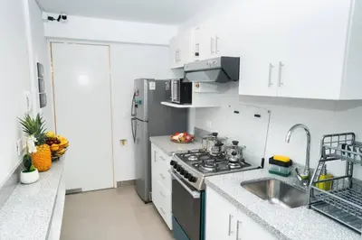a white kitchen with a stove and a sink at Hermoso departamento de 3 habitaciones in Lima
