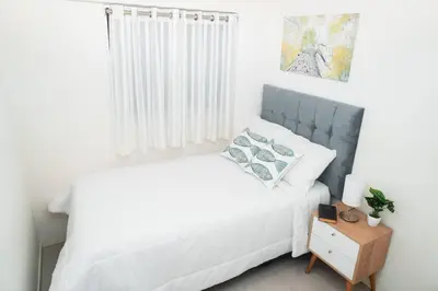 a bedroom with a white bed and a night stand at Hermoso departamento de 3 habitaciones in Lima