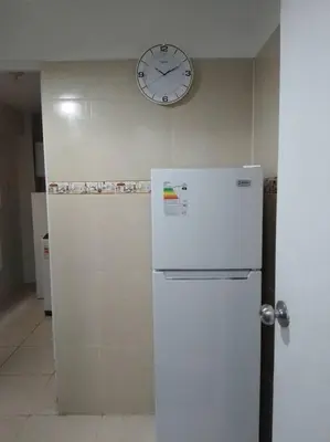a refrigerator in a kitchen with a clock on the wall at BONITO DEPARTAMENTO EN MIRAFLORES in Lima