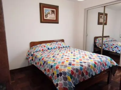 a bedroom with a bed with a colorful comforter at BONITO DEPARTAMENTO EN MIRAFLORES in Lima