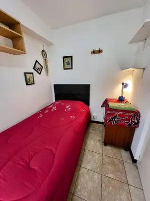 a bedroom with a red bed and a table at Private Cozy room with batroom in Miraflores in Lima