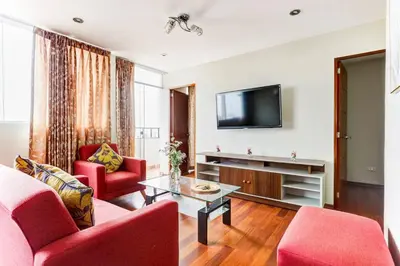 a living room with two red chairs and a tv at Apartamentos Estela en Alameda colonial - 5km Aeropuerto Jorge Chávez in Lima