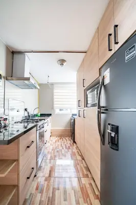 a kitchen with a stainless steel refrigerator and wooden floors at Apartamentos Estela en Alameda colonial - 5km Aeropuerto Jorge Chávez in Lima