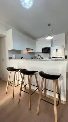 a kitchen with a white counter and two bar stools at APARTAMENTO KELVIN - Edificio ON APARTMENTS in Lima