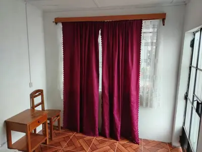 a red curtain in a room with a wooden table at Hospedaje Olguita in Oxapampa