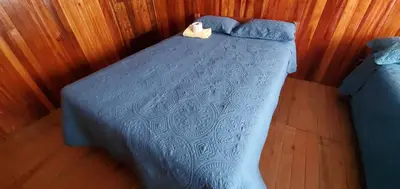 a bed with a blue comforter in a bedroom at Hospedaje Olguita in Oxapampa