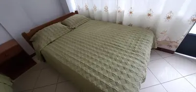 a bed with a green comforter in a bedroom at Hospedaje Olguita in Oxapampa