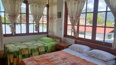 a bedroom with two beds and large windows at Hospedaje Olguita in Oxapampa