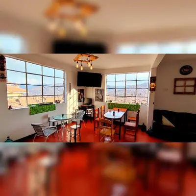 a living room with a table and chairs and windows at Antis Apartment in Cusco