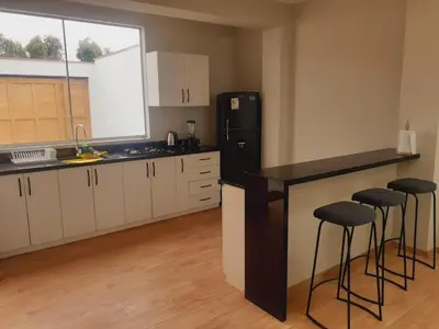 a kitchen with a black refrigerator and bar stools at Hermosa Casa de Playa km 90.5 in Bujama Baja