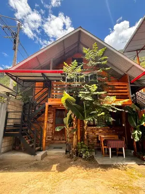 a wooden house with a tree in front of it at Fachwerkhaus zum Hirsch in Oxapampa