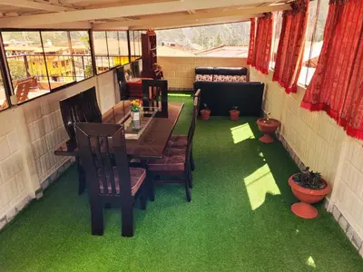 a room with a table and chairs and green grass at Hostal EL VIAJERO en Ollantaytambo in Ollantaytambo