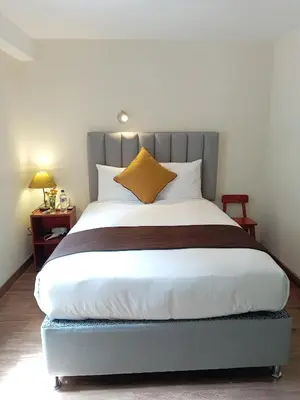 a bedroom with a large bed with a gray headboard at Hotel Pucara Machupicchu in Machu Picchu