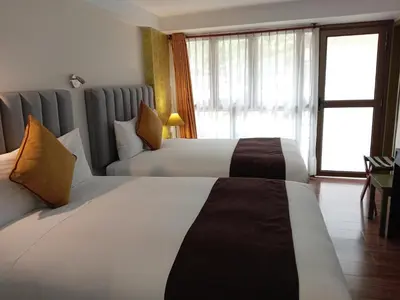 a hotel room with two beds and a window at Hotel Pucara Machupicchu in Machu Picchu