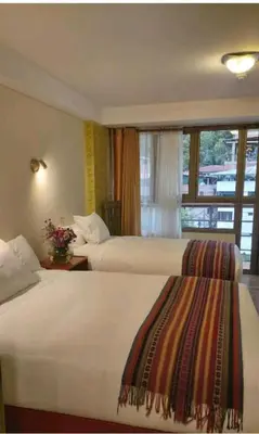 a hotel room with two beds and a window at Hotel Pucara Machupicchu in Machu Picchu
