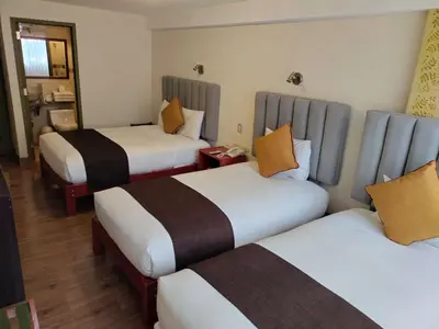 a hotel room with three beds with orange pillows at Hotel Pucara Machupicchu in Machu Picchu