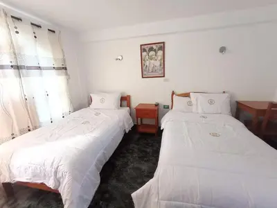 two beds in a room with white sheets at Hotel MESONERO in Ayacucho