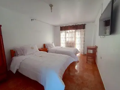 a bedroom with two beds and a television in it at Hotel MESONERO in Ayacucho