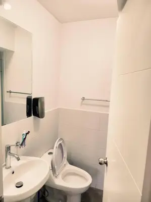 a white bathroom with a toilet and a sink at San Miguel Exclusivo Depa Vista al Mar, piscina in Lima