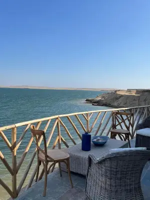 a table and chairs on a balcony overlooking the ocean at Atenas Hotel Boutique in Paracas