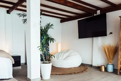 a living room with a white chair and a flat screen tv at Atenas Hotel Boutique in Paracas