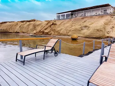 a wooden dock with two benches on the water at Atenas Hotel Boutique in Paracas