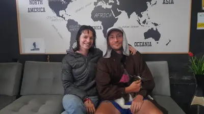 two people sitting on a couch with a cat at Mochileros in Lima