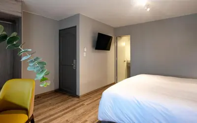 a bedroom with a bed and a yellow chair at ARTE HOTEL Lima in Lima