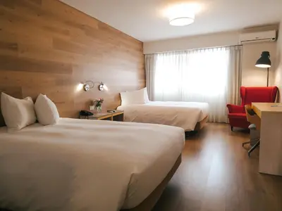 a hotel room with two beds and a red chair at ARTE HOTEL Lima in Lima