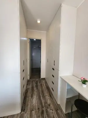 a walk in closet with white cabinets and wood floors at Dpto acogedor con terraza privada in Lima