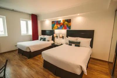 a hotel room with two beds and a painting on the wall at El Polo Hotel & Suites in Lima