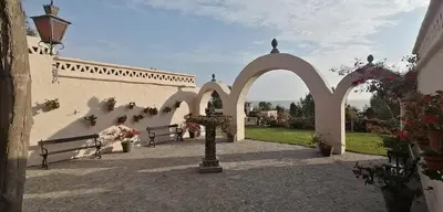 a courtyard with two benches and an archway with flowers at Darenas Hacienda in Aucallama