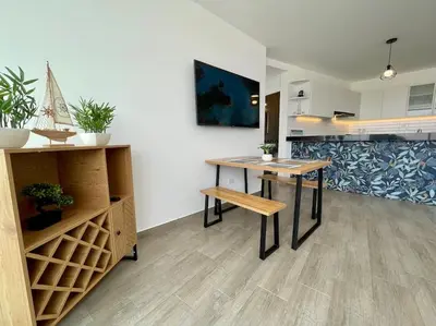 a dining room with a table and a kitchen at Moderno Departamento con Piscina y Parrilla, 3 min de la playa, Asia in Asia