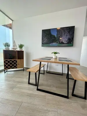 a dining room with a table and benches at Moderno Departamento con Piscina y Parrilla, 3 min de la playa, Asia in Asia