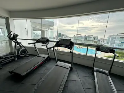 a gym with three treadmills in front of a window at Moderno Departamento con Piscina y Parrilla, 3 min de la playa, Asia in Asia