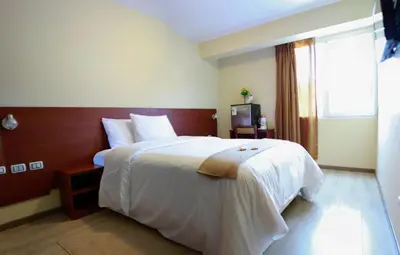 a bedroom with a large bed with white sheets and a window at Hotel Las Palmas in Lima