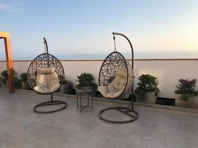two wicker chairs sitting on a balcony with plants at Departamento exclusivo con vista al mar in Lima