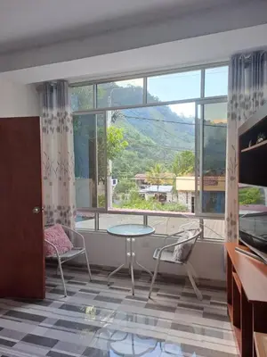 a living room with a table and chairs and a large window at Mi Chanchamayo, family. in La Merced