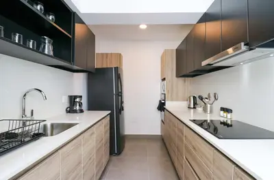 a kitchen with wooden cabinets and a black refrigerator at Actual by Wynwood House in Lima