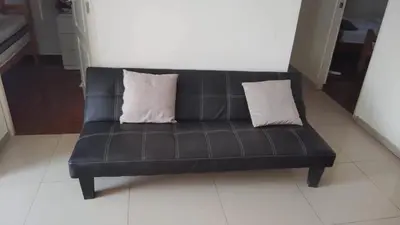 a black leather couch with two white pillows on it at Casa en cineguilla in Cieneguilla