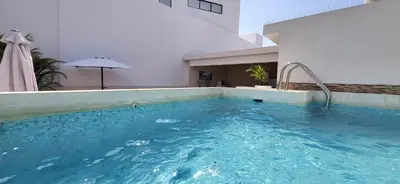 a swimming pool in a building with an umbrella at L & P Apart Punta Hermosa in Punta Hermosa