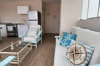 a living room with a couch and chairs and a kitchen at L & P Apart Punta Hermosa in Punta Hermosa