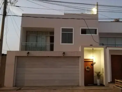 a white house with a garage and a door at L & P Apart Punta Hermosa in Punta Hermosa