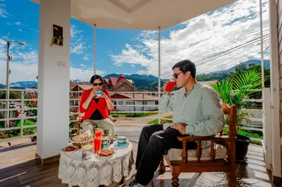 two people sitting on a porch with a table at Las Yungas Hospedaje in Oxapampa