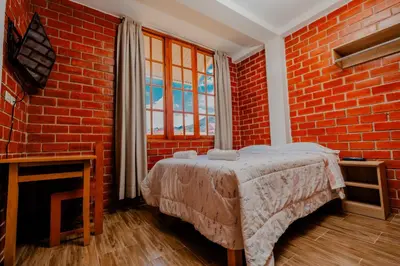 a bedroom with a bed in a brick wall at Las Yungas Hospedaje in Oxapampa