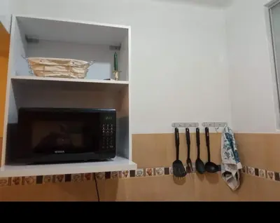 a microwave in a kitchen with utensils on a shelf at Paiva in Lima