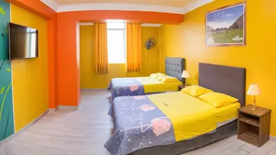 two beds in a room with yellow and orange walls at Hotel Savilayo in Ica